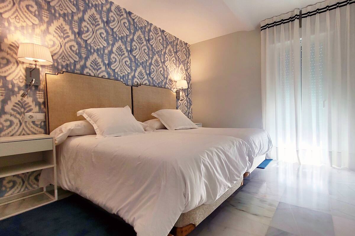 A neatly made bed with white linens in a hotel room.
