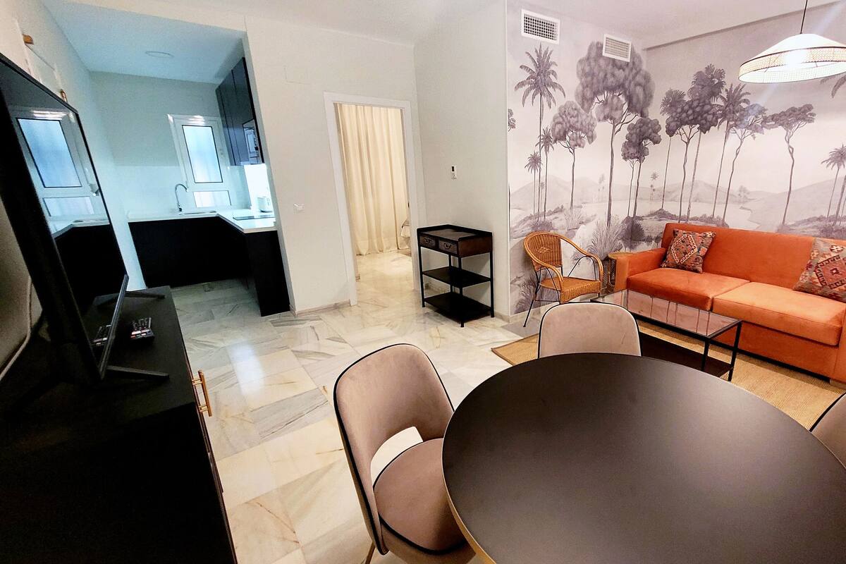 A living room with a sofa, chairs, a coffee table, and a TV.
