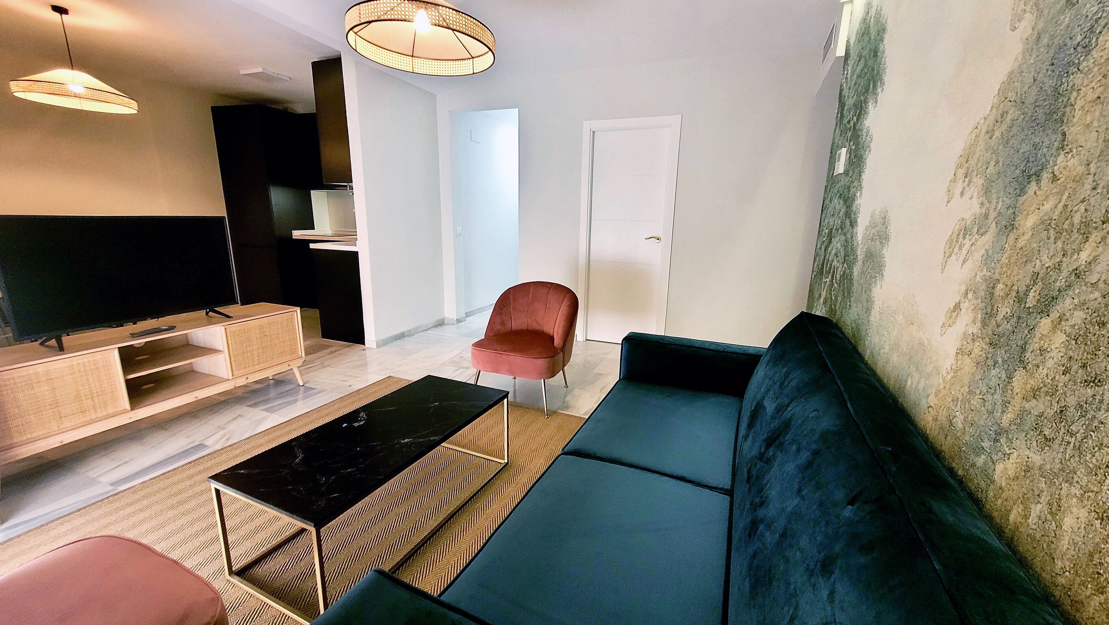 A modern living room with a black sofa, a wooden coffee table, a red chair, and a TV on a wooden stand.