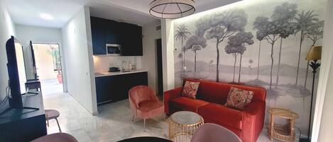 A modern living room with a red sofa, a small round table, and a wall mural of trees.