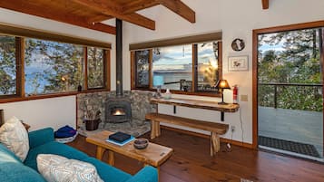Cozy living room with a fireplace, comfortable seating, and large windows offering views of the outdoors.