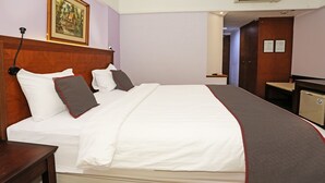 Ein Hotelzimmer mit einem großen Bett, einem Holzkopfschild und einem Gemälde an der Wand.