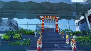 Entrada de un hotel con un letrero que dice "Vajram Kyriad" y una escalera decorada con coloridos arreglos florales.