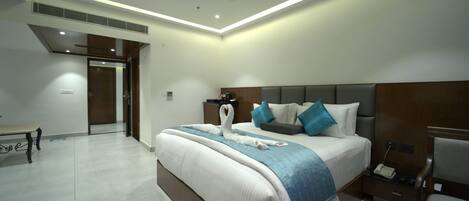 Una habitación de hotel moderna con una cama grande, mesitas de noche, un escritorio y un ventilador de techo.