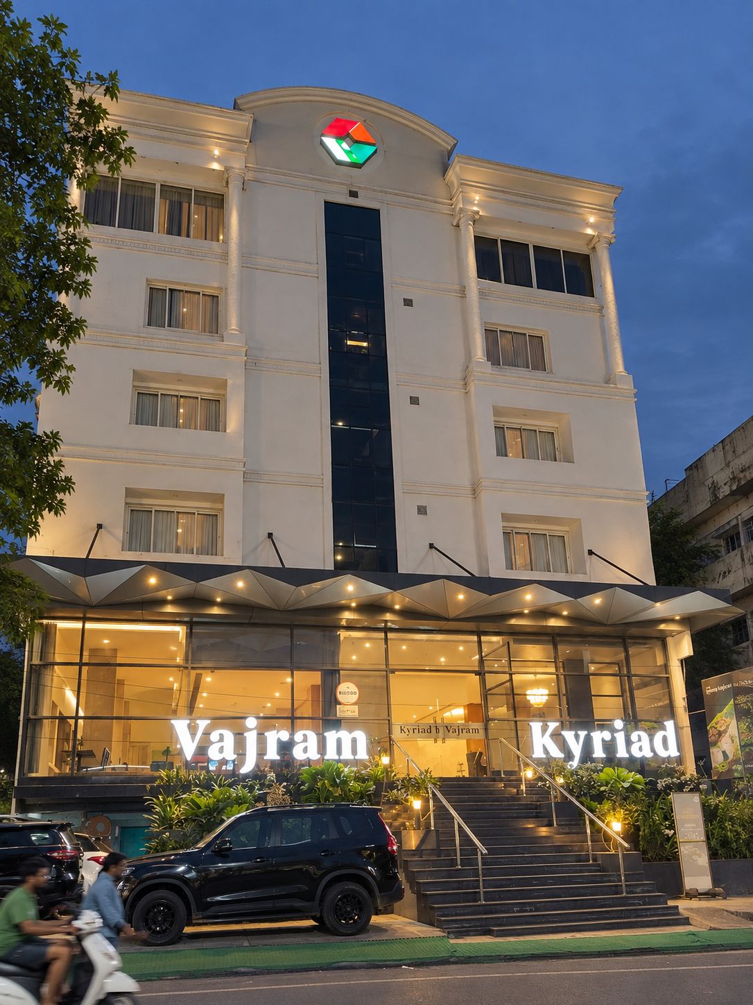 Un edificio de hotel con un cartel llamativo que dice 'Vajram Kyiad' y un logotipo sobre la entrada.