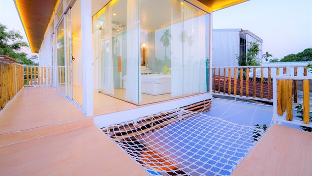 Una habitación de hotel moderna con pared de vidrio, terraza de madera y zona con mosquitera.