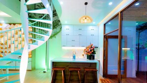 Una cocina moderna con una isla central, taburetes de bar y una escalera en espiral.