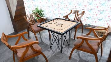 Een kamer met een tafelvoetbaltafel, omringd door houten stoelen.