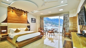 Quarto de hotel moderno com uma cama grande, uma escrivaninha e uma varanda com vista para as montanhas.