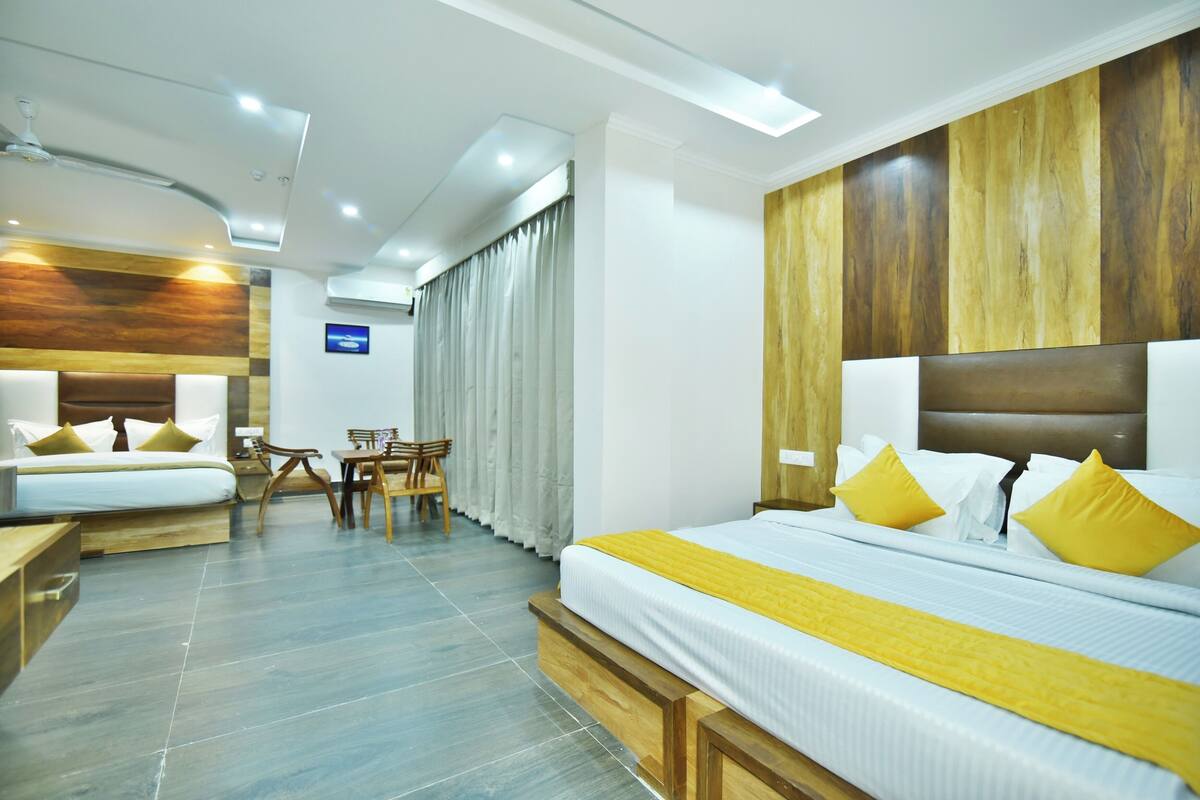 A hotel room with a large bed, a smaller bed, a desk, and a chair.