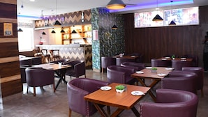 Um restaurante com paredes de madeira, cadeiras de couro roxo e um espaço de bar.