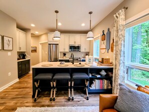 A modern kitchen with white cabinets, stainless steel appliances, and a central island with bar stools.