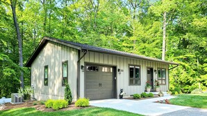 A single-story house with a garage, surrounded by a well-maintained lawn and trees. - Bear Mountain Cottage (Paeonian Springs)