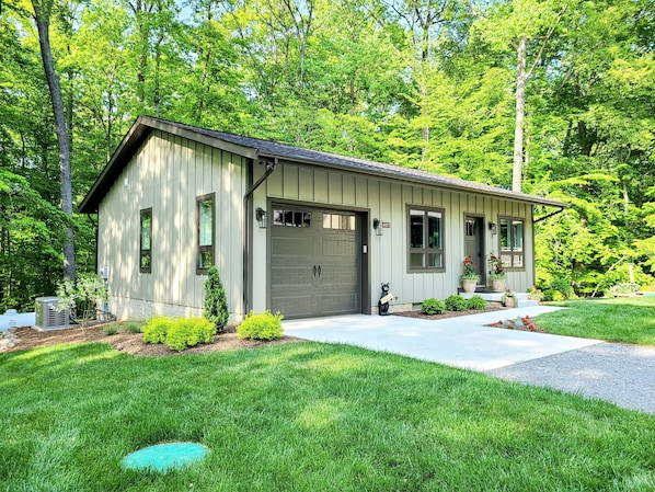 A single-story house with a garage, surrounded by a well-maintained lawn and trees.