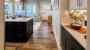 A modern kitchen with dark cabinets, a wooden floor, and a central island. - Bear Mountain Cottage (Paeonian Springs)