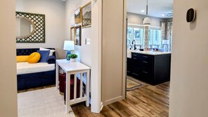 A modern kitchen with a large island, wooden flooring, and a view to the dining area. - Bear Mountain Cottage (Paeonian Springs)