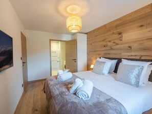 A bedroom with a wooden headboard, a bed with white linens, and a rolled towel on the bed.