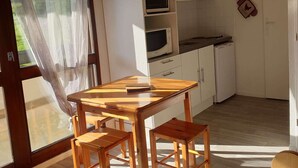Eine Küche mit Holztisch, Bänken, weißen Schränken und einer Mikrowelle.