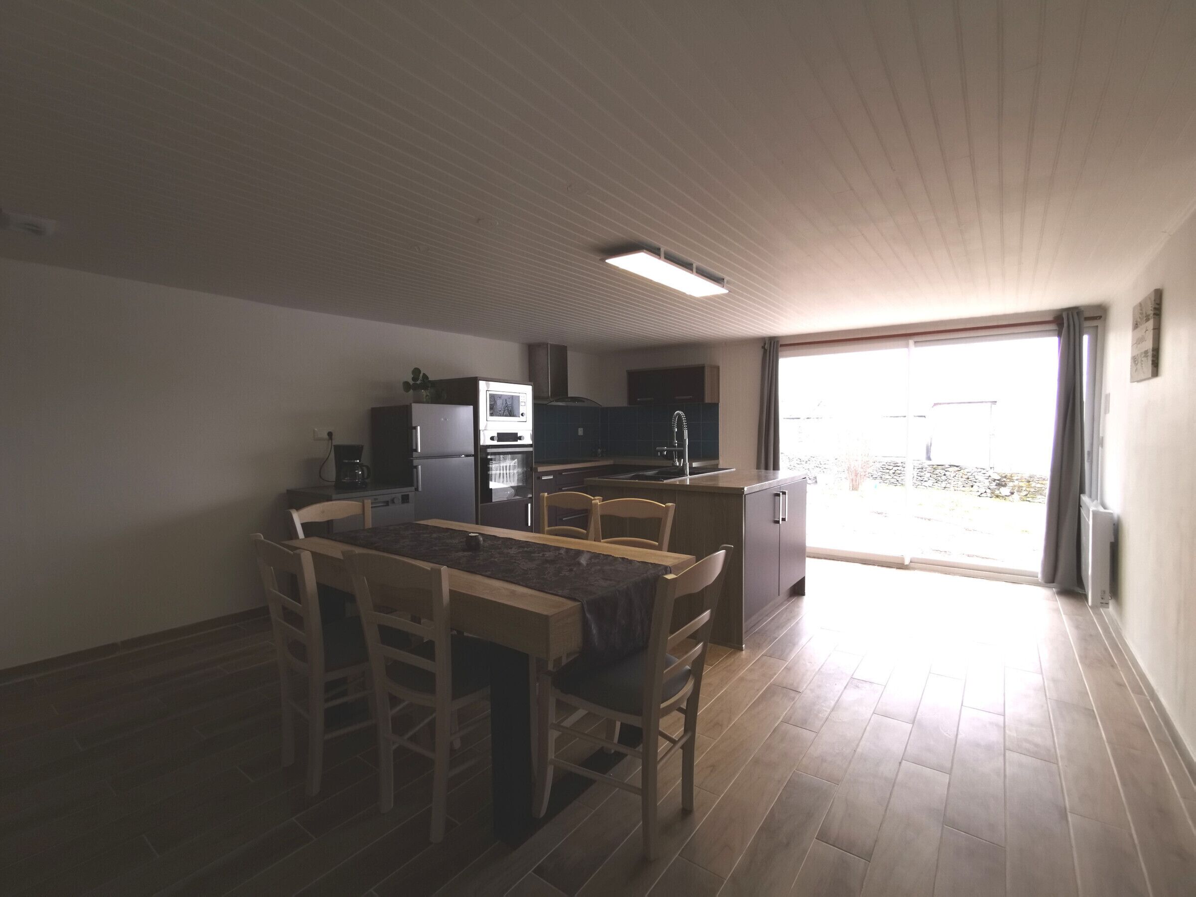 Cocina compacta con zona de comedor, horno integrado y un amplio ventanal que ofrece luz natural.
