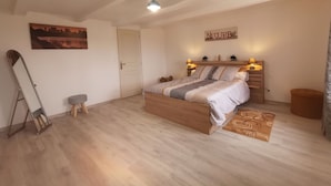 A bedroom with a wooden bed, a cityscape painting, a 'NATURE' sign, and a small stool. - Charming Farmhouse Retreat: Farm Life, Wildlife & Scenic Views, Perfect for Family Holidays (Autrac)