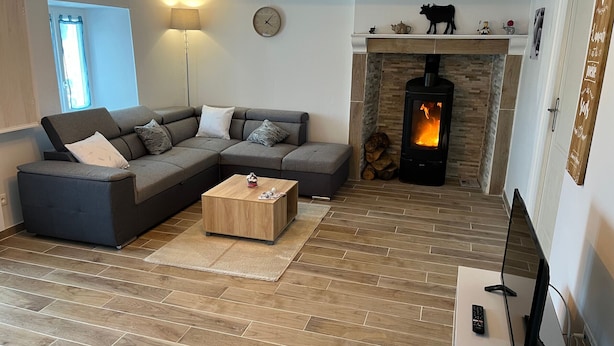 A modern living room with a sectional sofa, a wooden coffee table, a fireplace, and a TV. - Charming Farmhouse Retreat: Farm Life, Wildlife & Scenic Views, Perfect for Family Holidays (Autrac)