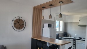 Eine moderne Küche mit einer Holztheke, schwarzen Barhocker, einer Mikrowelle und einem Kühlschrank.