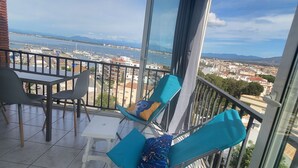 Ein Balkon mit Tisch und Stühlen, der Blick auf einen Yachthafen und die Stadt bietet.