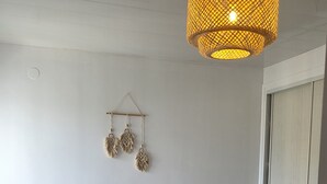 Ein Schlafzimmer mit einem Bett, einer Hängeleuchte und einer Wanddekoration.