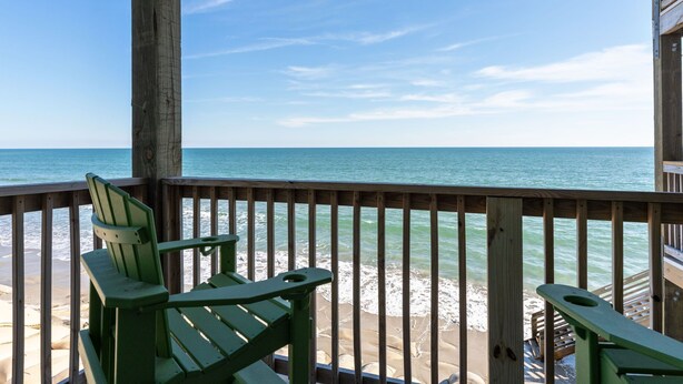 A wooden deck with two green Adirondack chairs facing a beach with ocean views. - Sunshine Paradise: Oceanfront Retreat Awaits (North Topsail Beach)