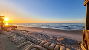 A beach view with a wooden structure and a row of sand-filled tires. - Sunshine Paradise: Oceanfront Retreat Awaits (North Topsail Beach)