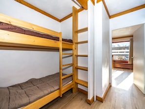 Une chambre de dortoir avec des lits superposés, des étagères en bois et une fenêtre donnant sur un bâtiment.