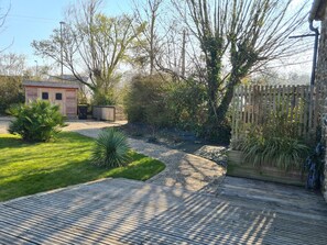 A wooden deck, a small shed, and a fenced area with various plants. - Comfortable house with private garden in Réville (Réville)