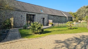 Un bâtiment en pierre doté d’un toit en pente, d’une allée en gravier et d’un jardin clos.