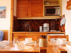 Une cuisine avec des meubles en bois, un four à micro-ondes, une machine à café et un dosseret carrelé.