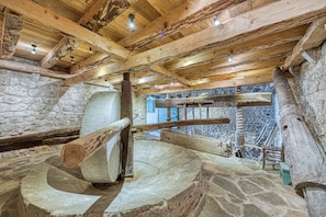 Un interior rústico con paredes de piedra, vigas de madera y una escalera en espiral de piedra.