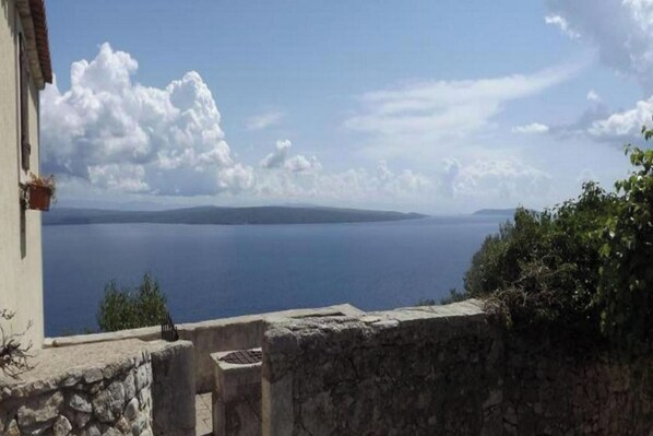 A stone wall with a view of a calm sea and distant land.
