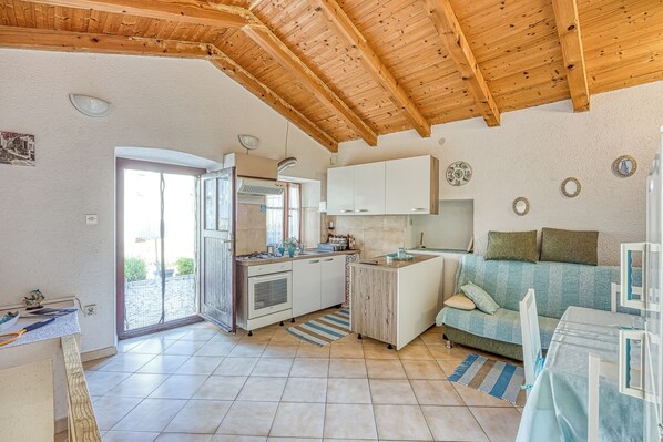 A compact kitchen with a wooden ceiling, a dining area with a table and chairs, and a sofa.