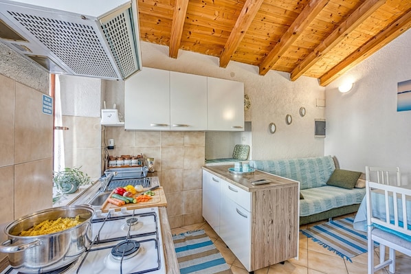 Cocina compacta con estufa, lavamanos y armarios blancos.