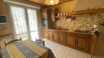 Une cuisine avec des meubles en bois, un dosseret carrelé et une table à manger recouverte d’une nappe.