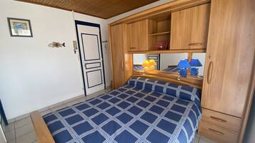 Une chambre à coucher avec un lit, une armoire en bois et une petite table avec des lampes.