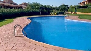 Une piscine à bord incurvé, entourée d’un chemin pavé en briques.