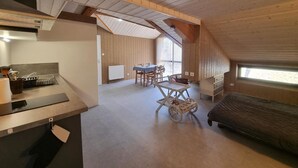 A cozy attic room with a kitchen area, a dining table, and a sofa. - Spacious lodge with fireplace and forest terrace, pets allowed (La Versanne)