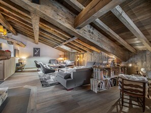 A rustic loft with exposed wooden beams, a grey sofa, and a wooden coffee table.