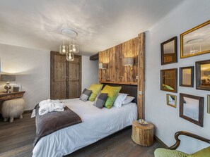 Una camera da letto con una testiera in legno, un letto con molti cuscini, un comodino, una lampada e uno specchio a parete.