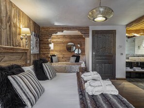 Una habitación acogedora con pared de madera, un sofá con almohadones a rayas, una manta de piel y un banco con toallas.