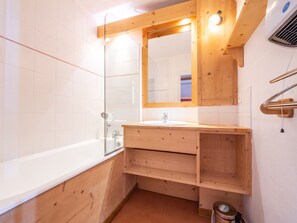 Un baño moderno con tocador de madera, cabina de ducha con vidrio y lavamanos empotrado.