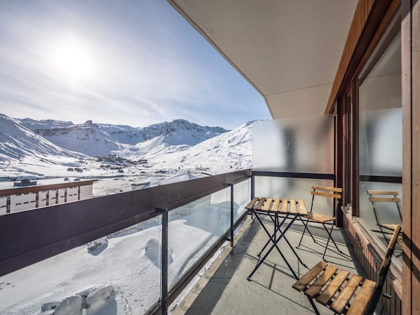 A balcony with a view of snow-covered mountains and a clear sky.