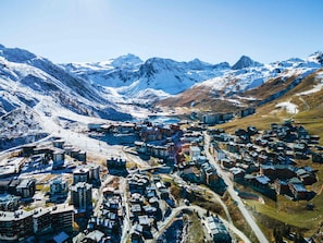 A mountainous town with snow-covered peaks, a mix of modern and traditional buildings, and a winding road through the valley.