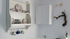 A compact kitchen with white cabinetry, a small dining table, and a compact dishwasher. - Cycladic Charming Studio in Mykonos (Mykonos)