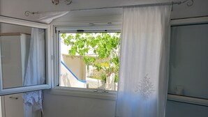 A room with a window, white curtains, and a view of greenery outside. - Cycladic Charming Studio in Mykonos (Mykonos)